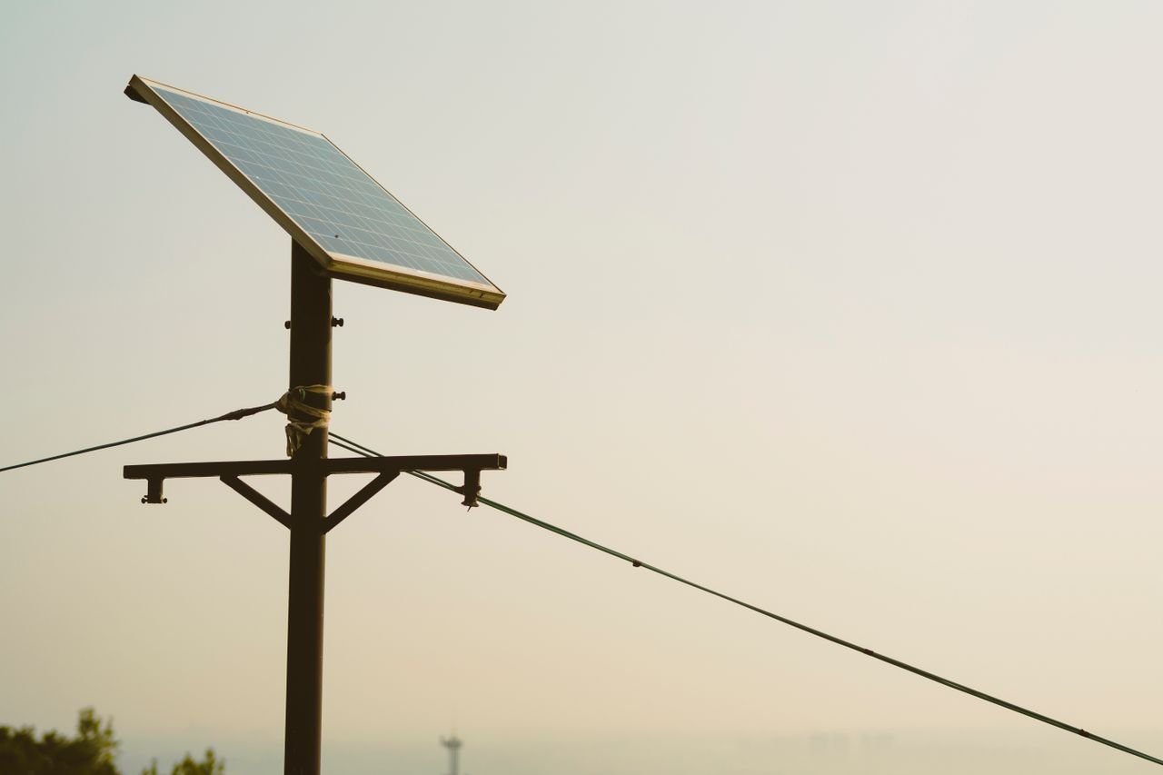 our-stories A single solar panel mounted on a tall post against a clear sky, symbolizing renewable energy.